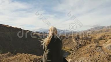 年轻女子站在悬崖边，举起<strong>双</strong>手，迎着高高的岩石山，在那里晒<strong>太阳</strong>